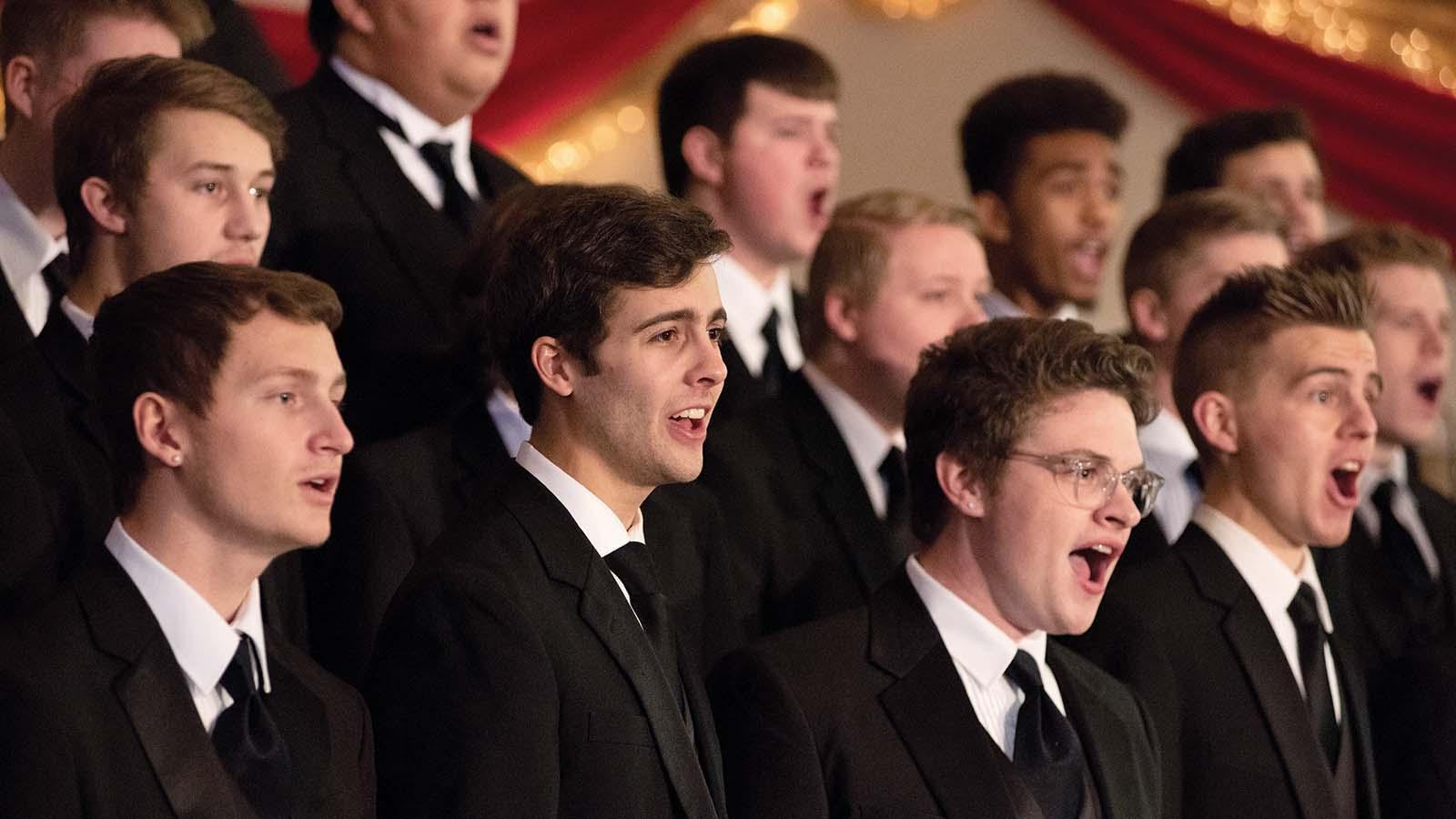 Closeup of men’s choir in tuxedos singing 